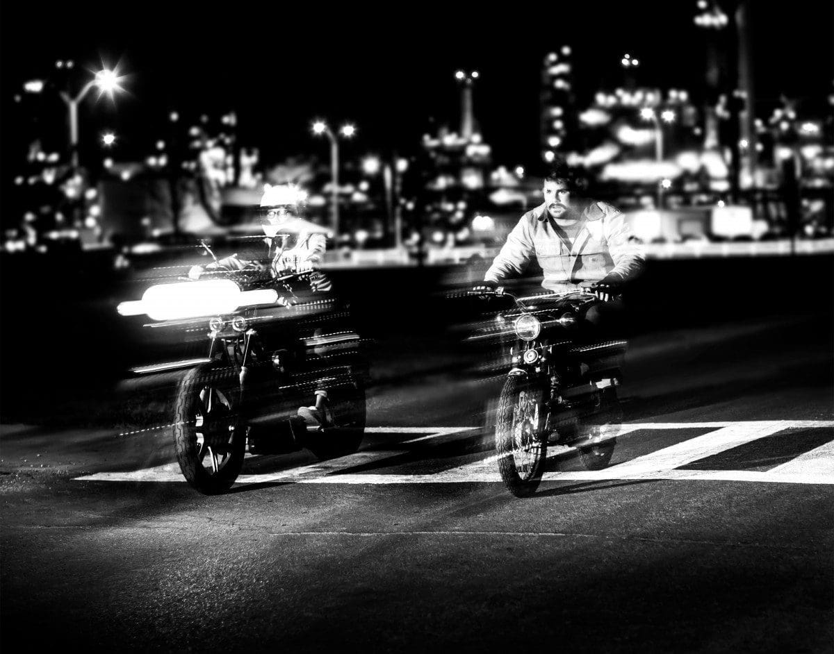 Two motorcycles at night near a zebra crossing blur