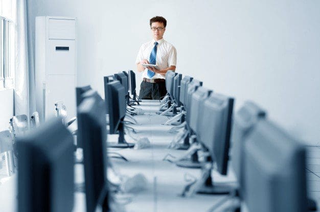 Desk with rows of computers and a man