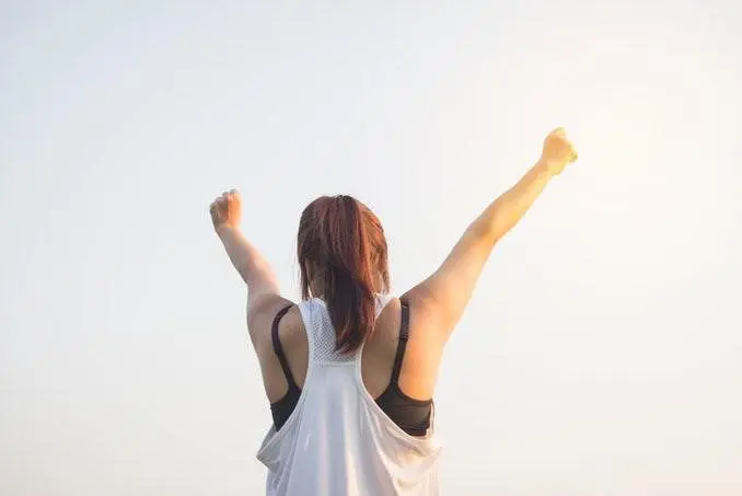 Back Of A Woman Raising Arms In The Sky