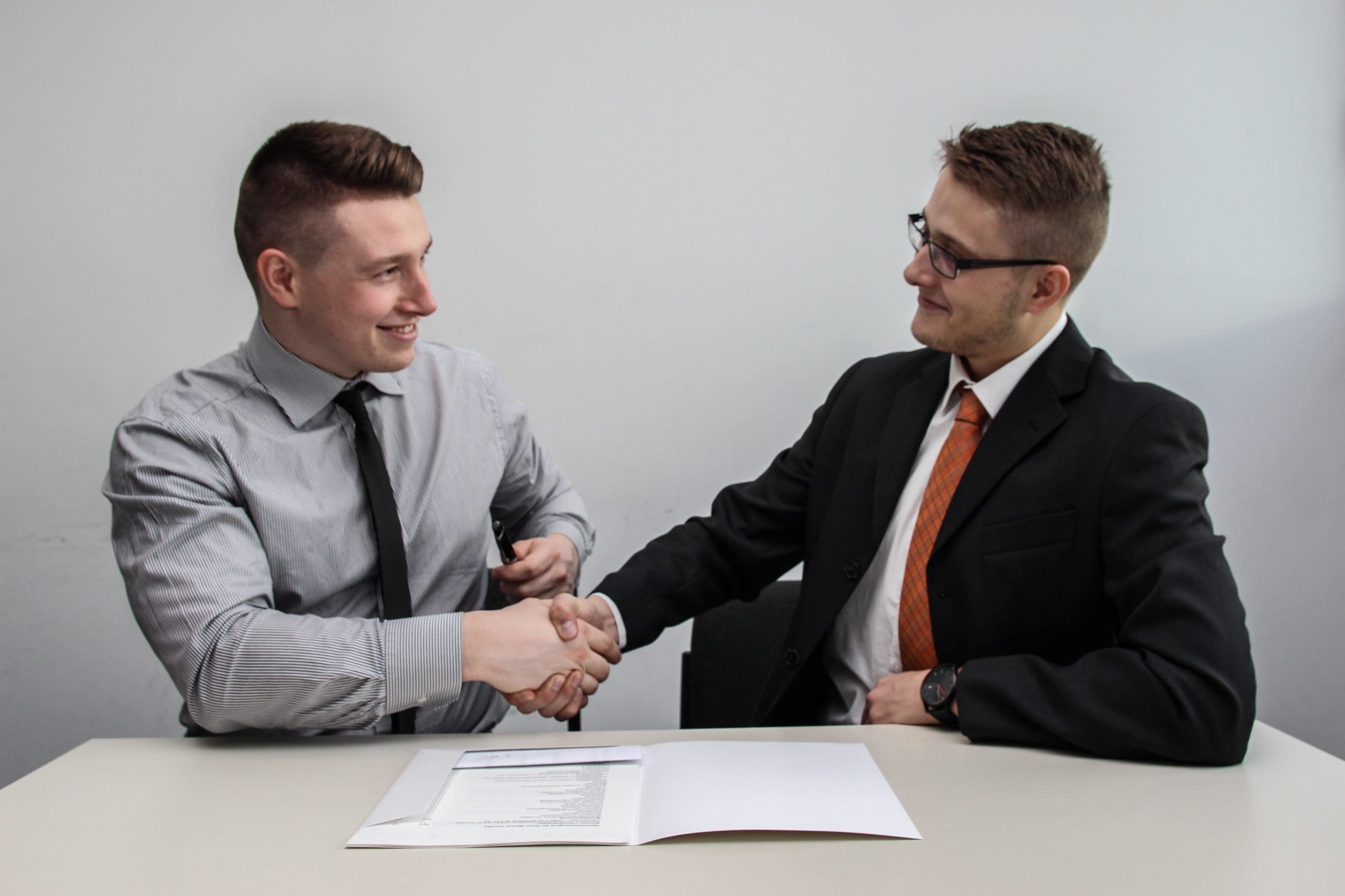 business partnership two men facing each other while shake hands and smiling