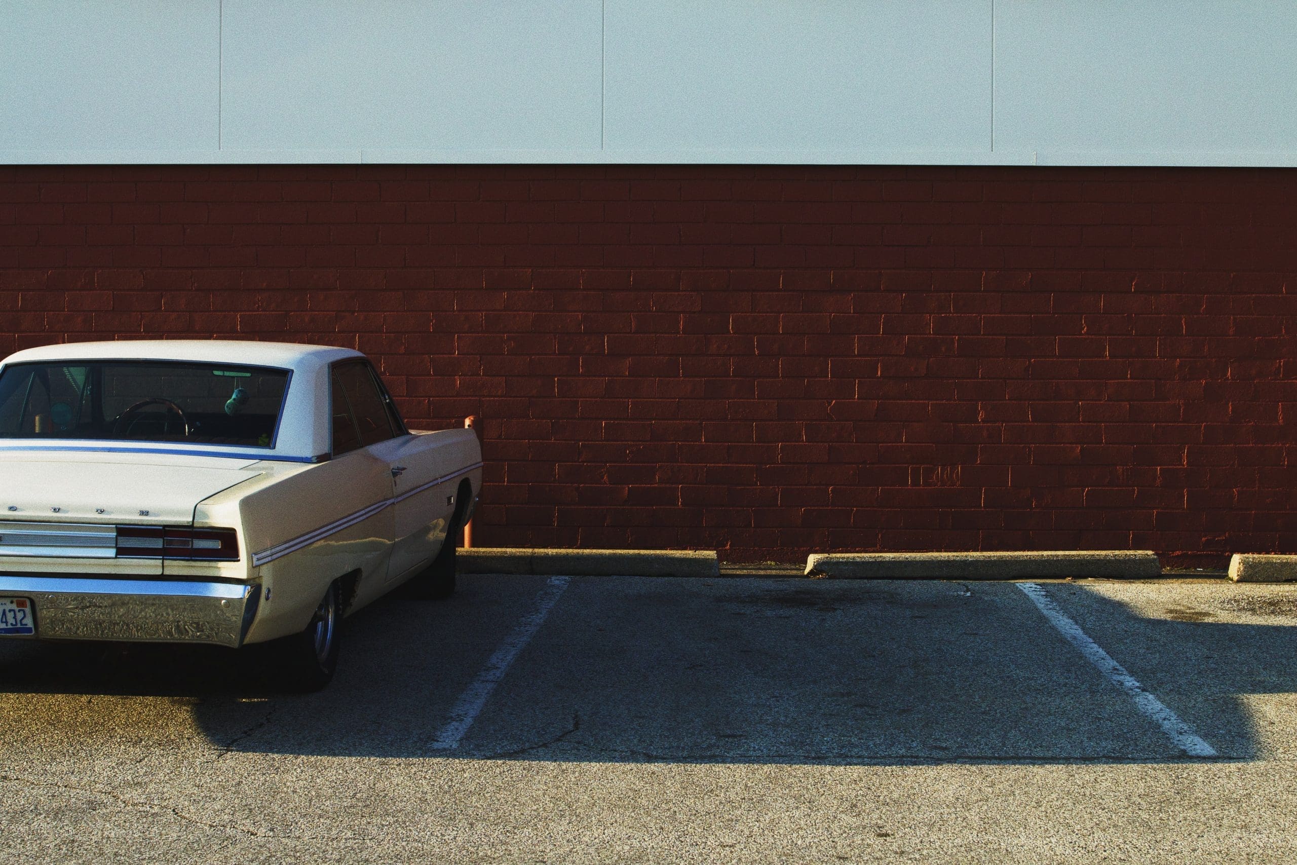 used car parked on parking lot near brown and white wall