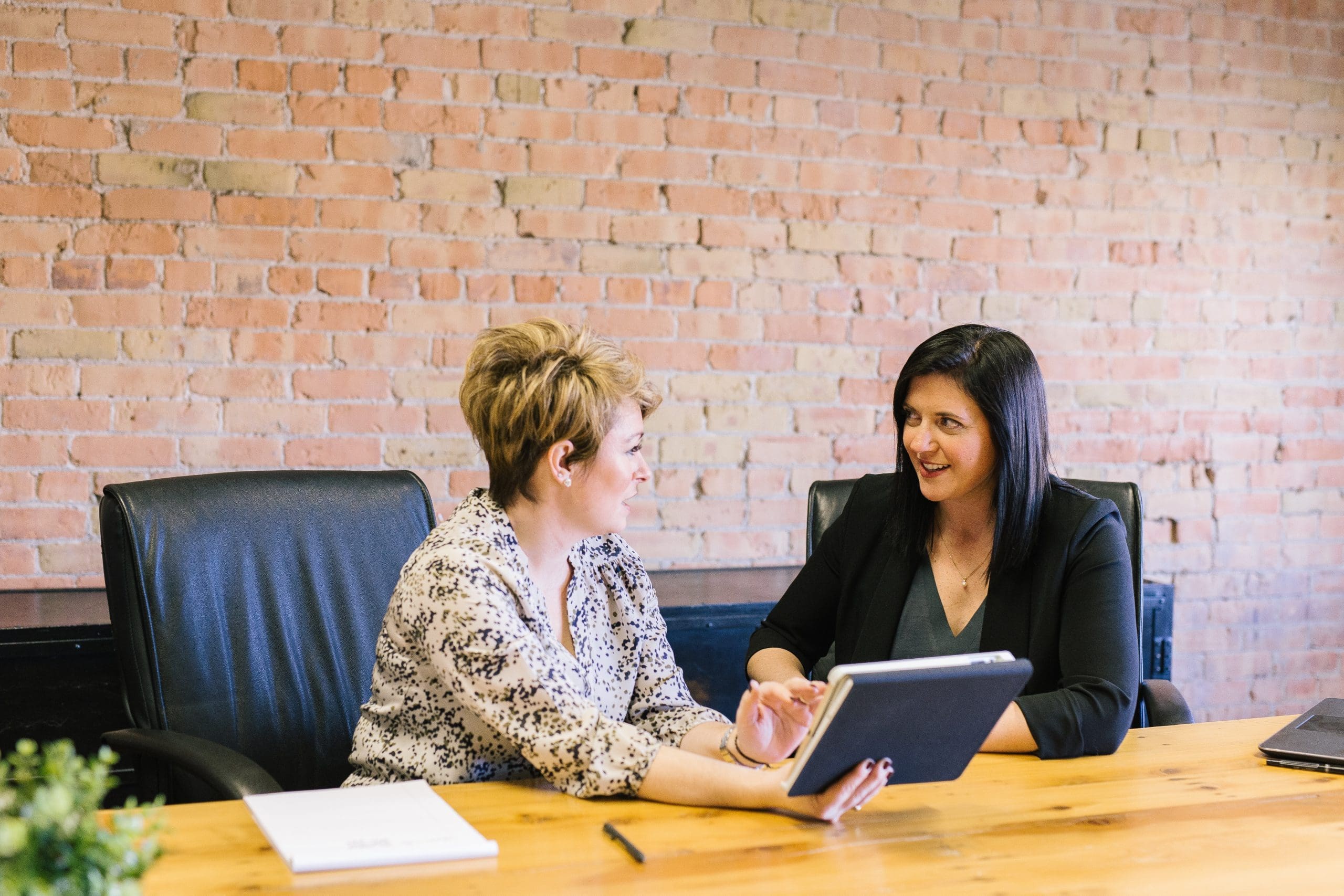 two women sitting on leather chairs in front of table Human Resources Consulting