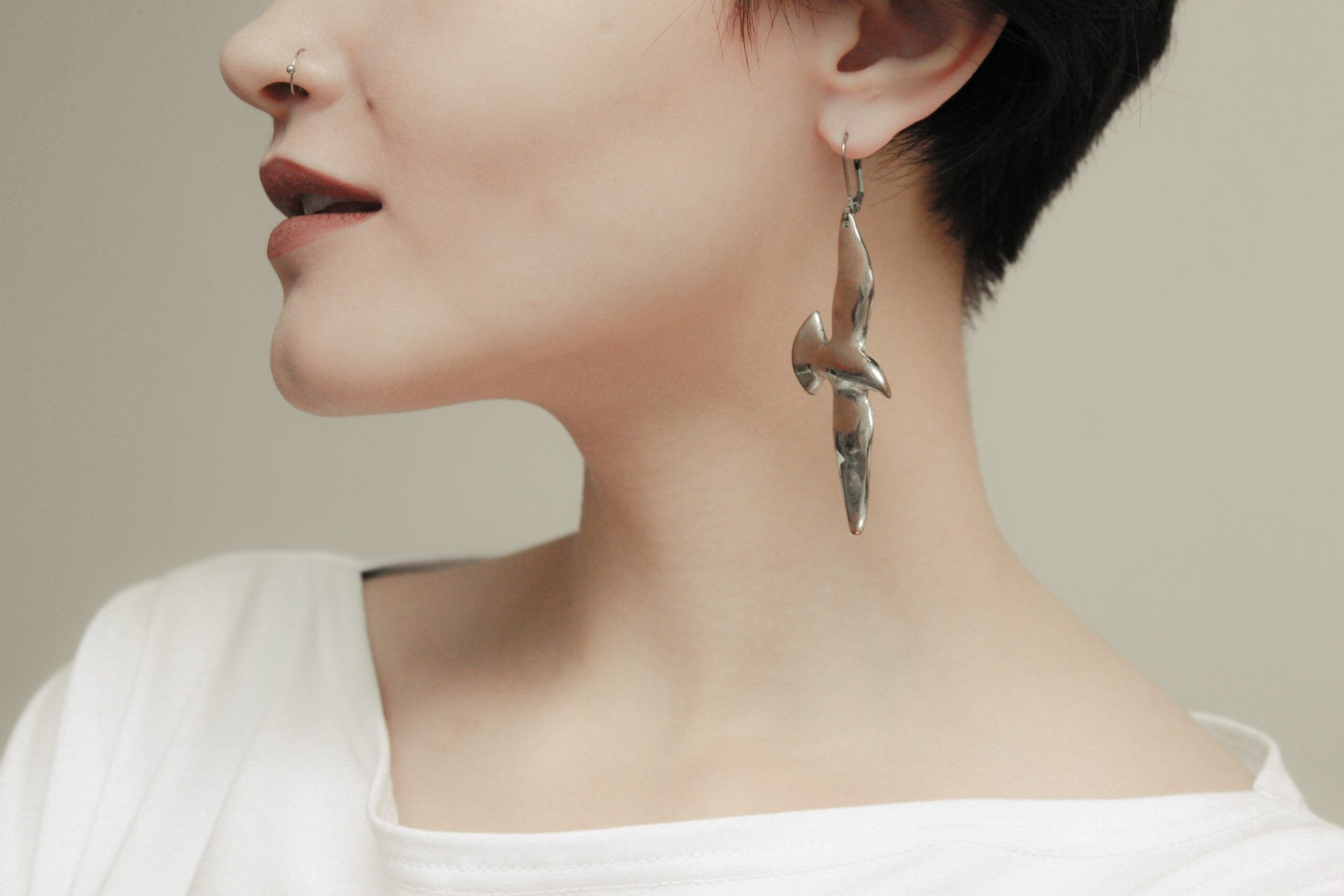 jewel designs woman in white scoop neck shirt wearing silver earrings