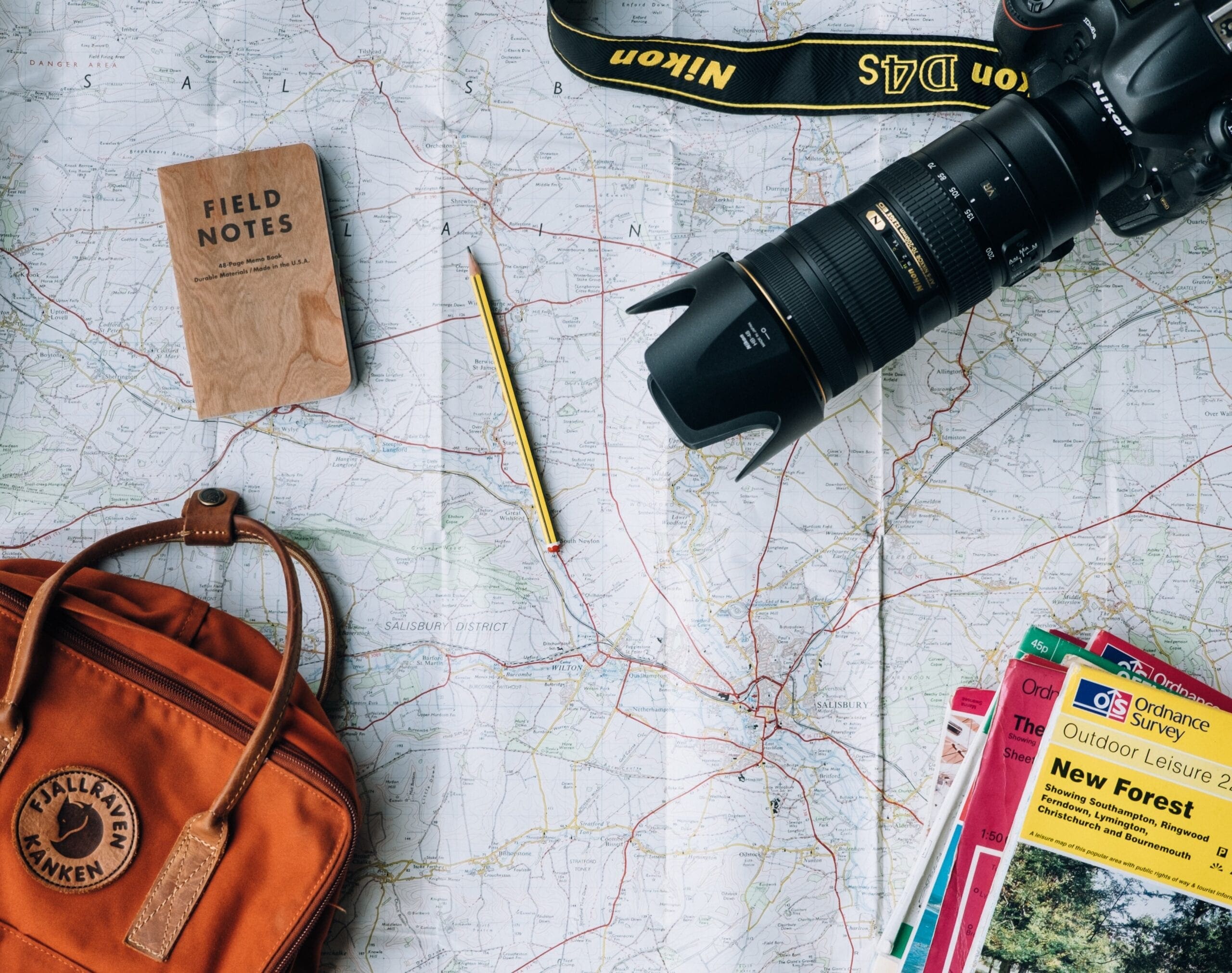 bucket list flat lay photography of camera, book, and bag