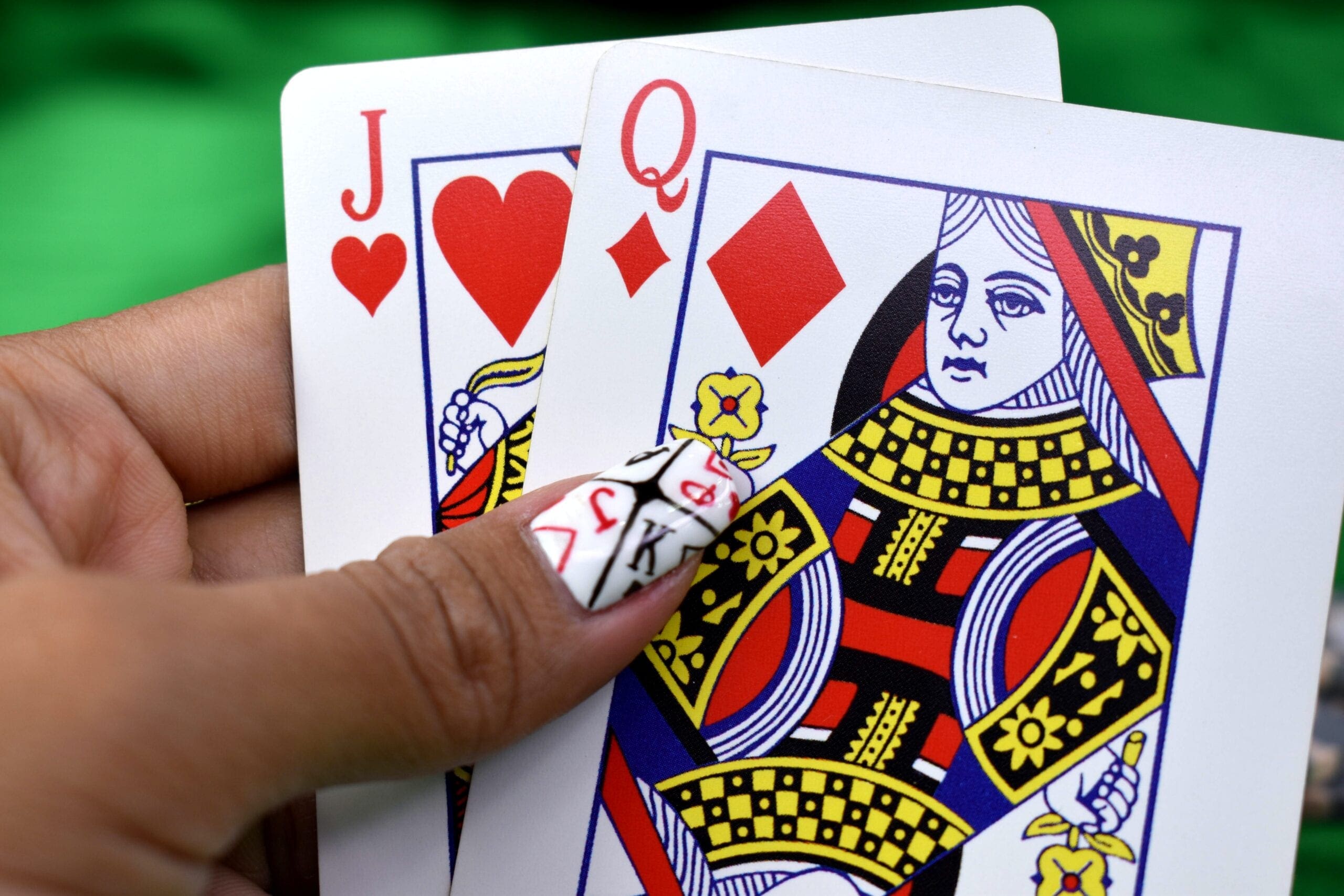 person holding queen of diamonds and jack of hearts playing cards responsible gambling