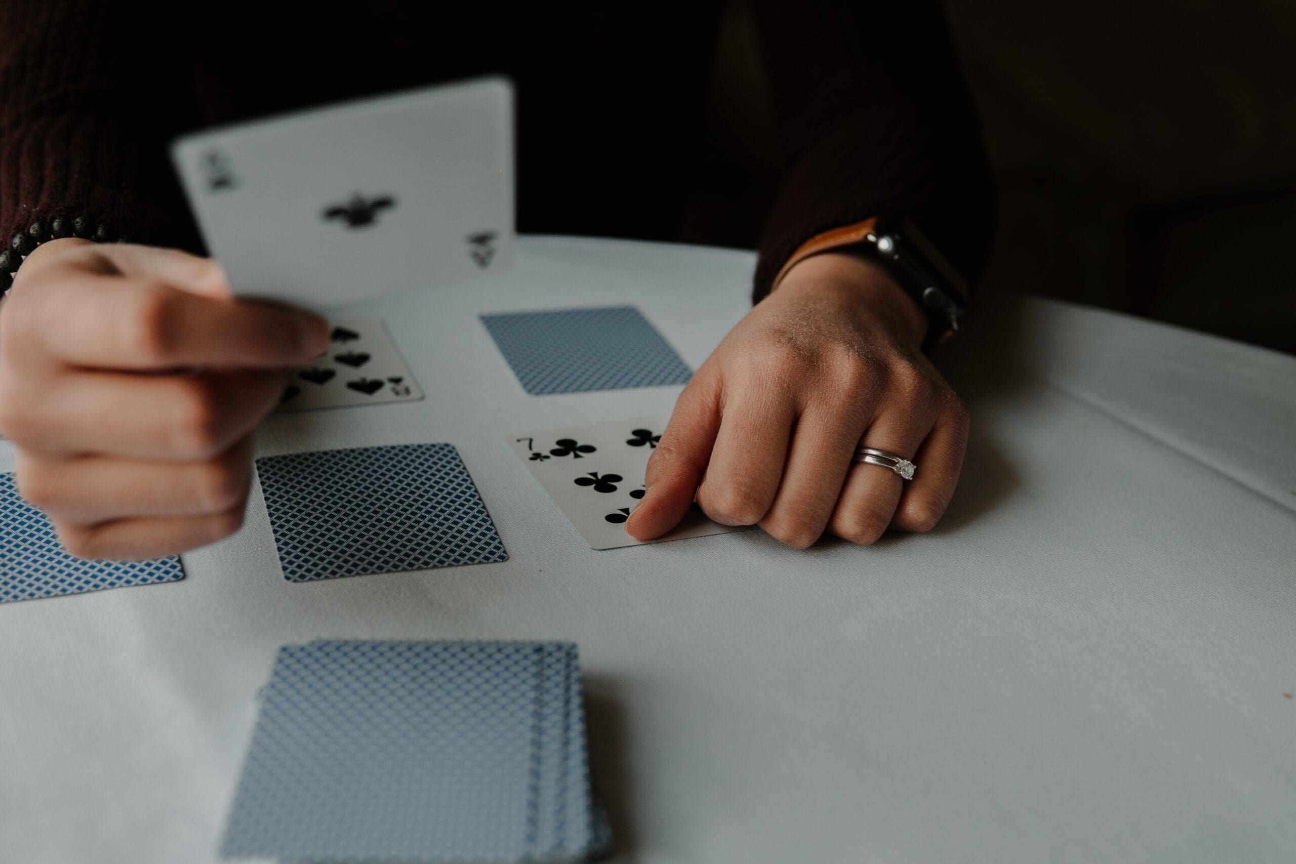 Photo by Andrik Langfield person holding playing cards on white table