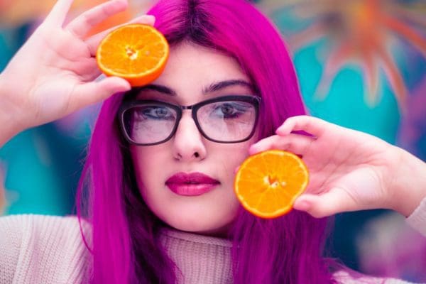 woman with red hair color holding sliced orange