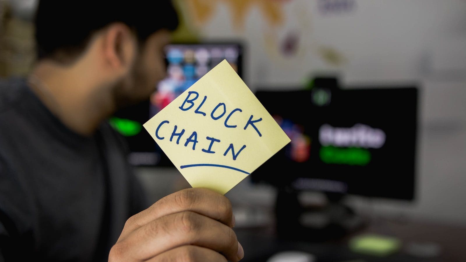 person holding sticky blockchain note