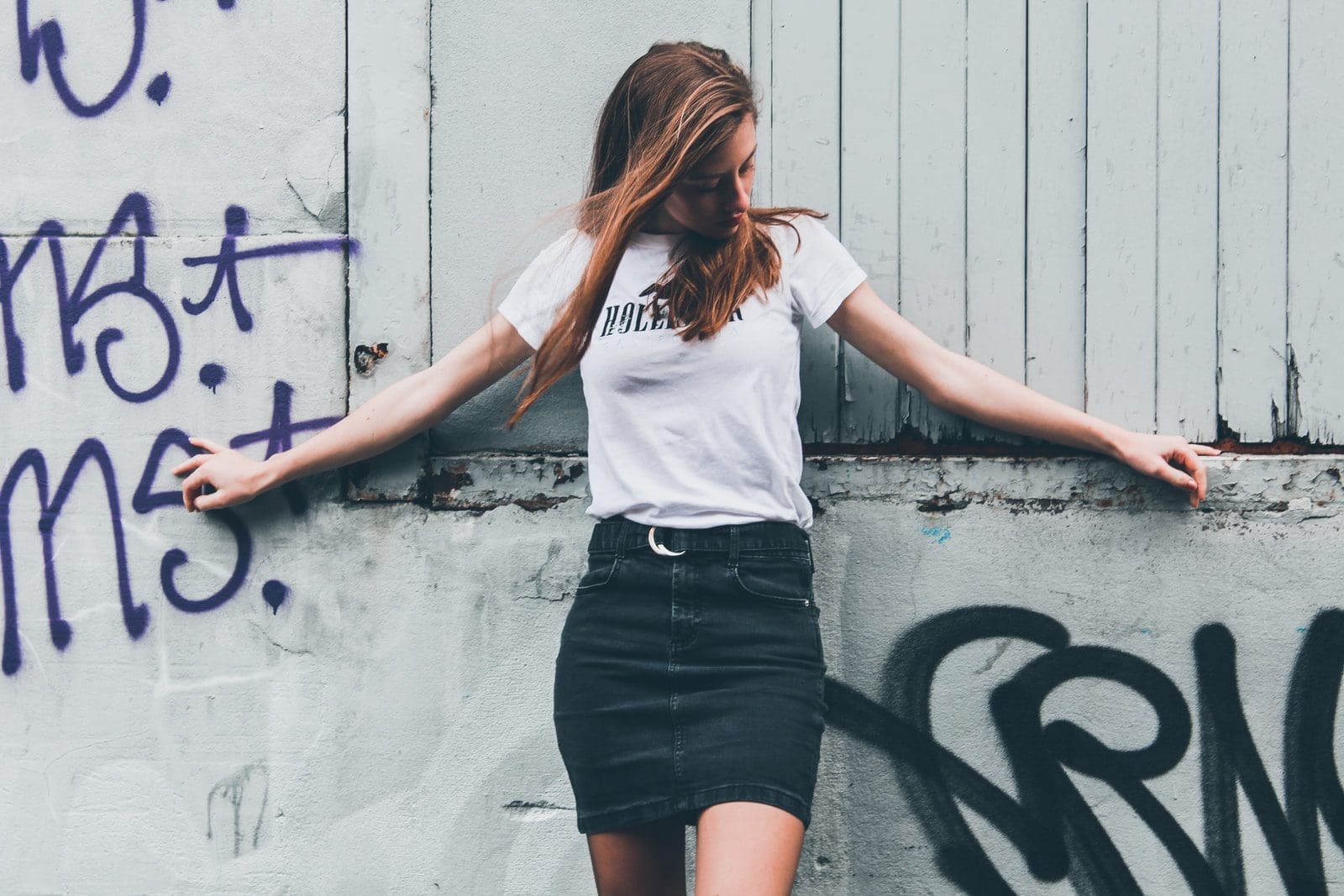 woman in white shirt and blackperfect skirt standing beside wall