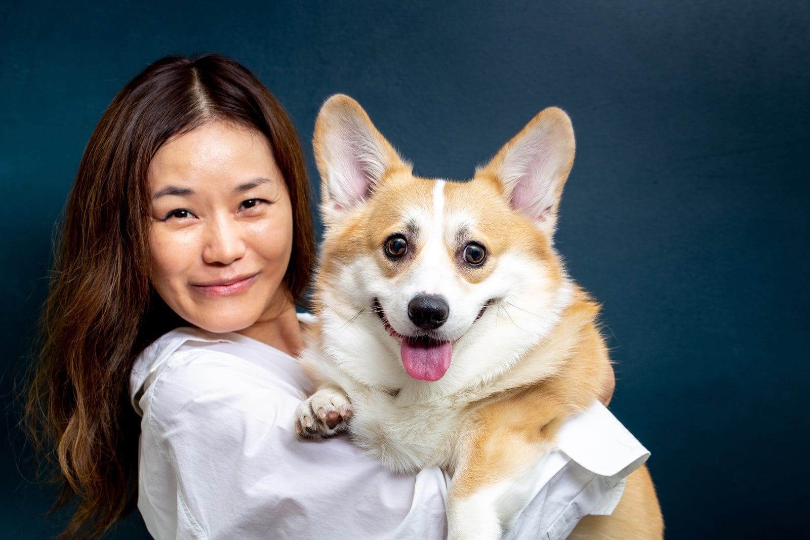 veterinary clinic woman in white shirt holding brown and white dog