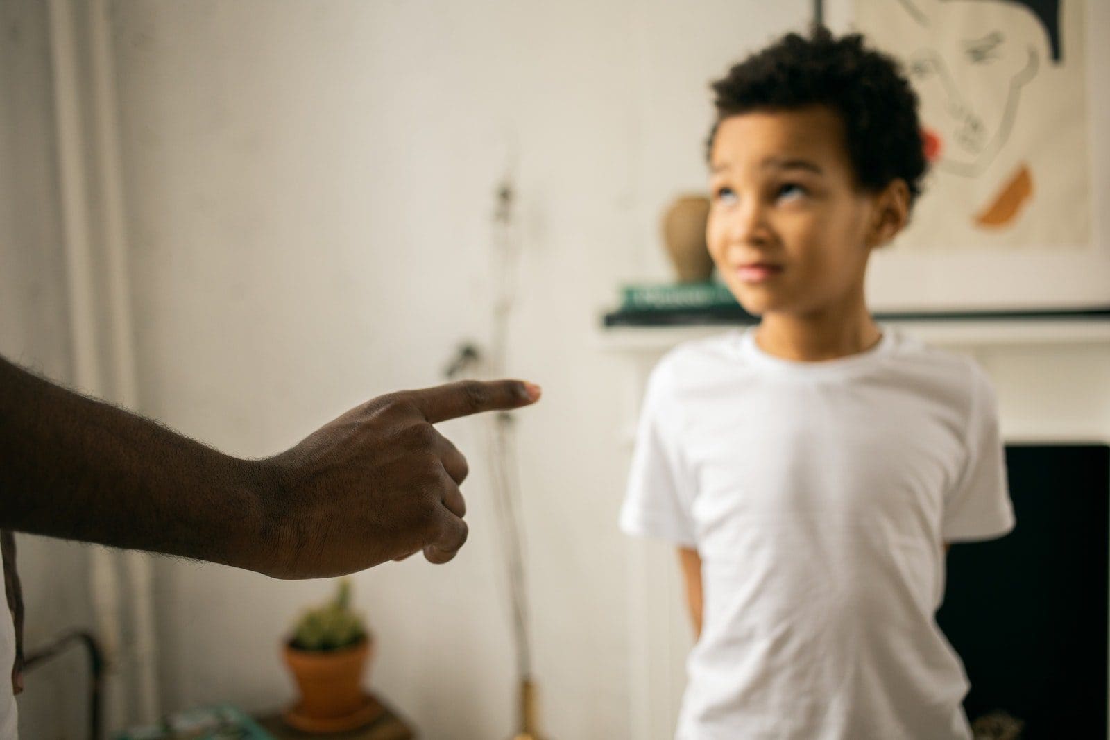 guilt and shame Upset little ethic boy looking at faceless father during argument