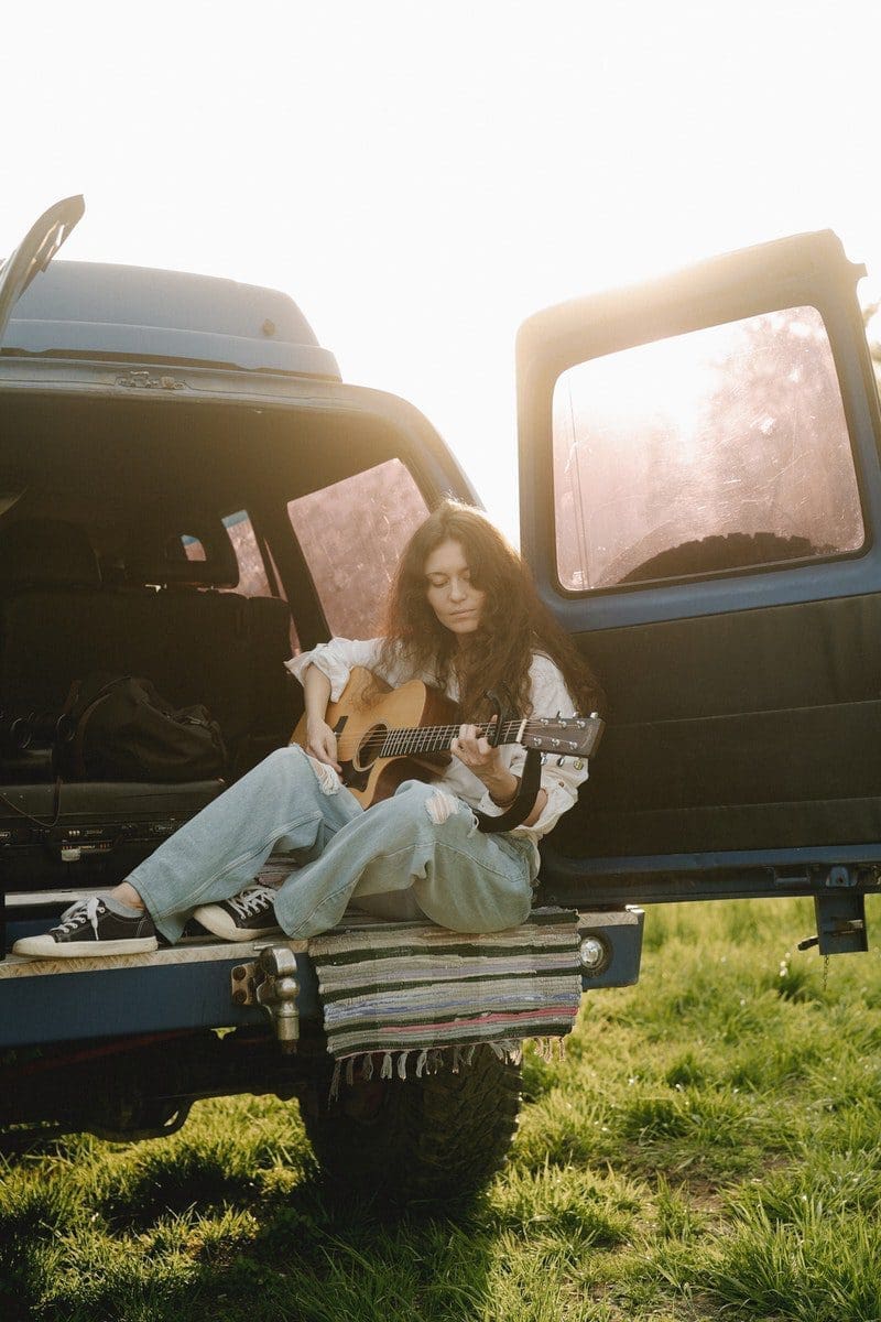 hippies A Woman Playing the Guitar at the Back of a Van