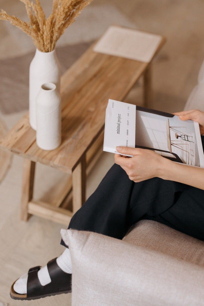 Person in Black Pants Holding White Printer Paper