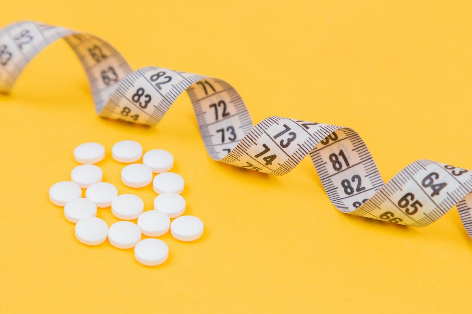 diet pills white round medication pill on yellow surface