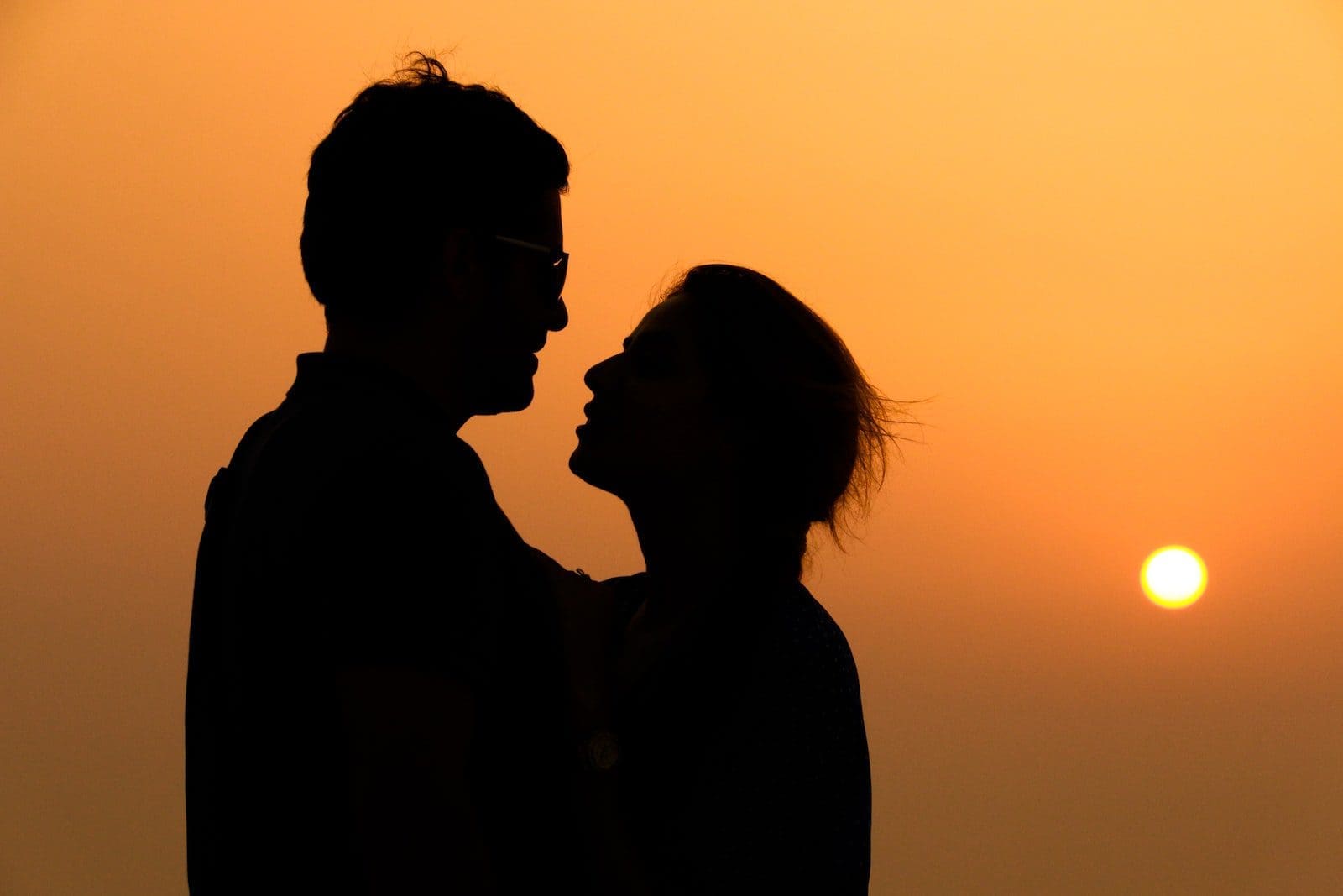 dating silhouette of woman wearing sunglasses during sunset