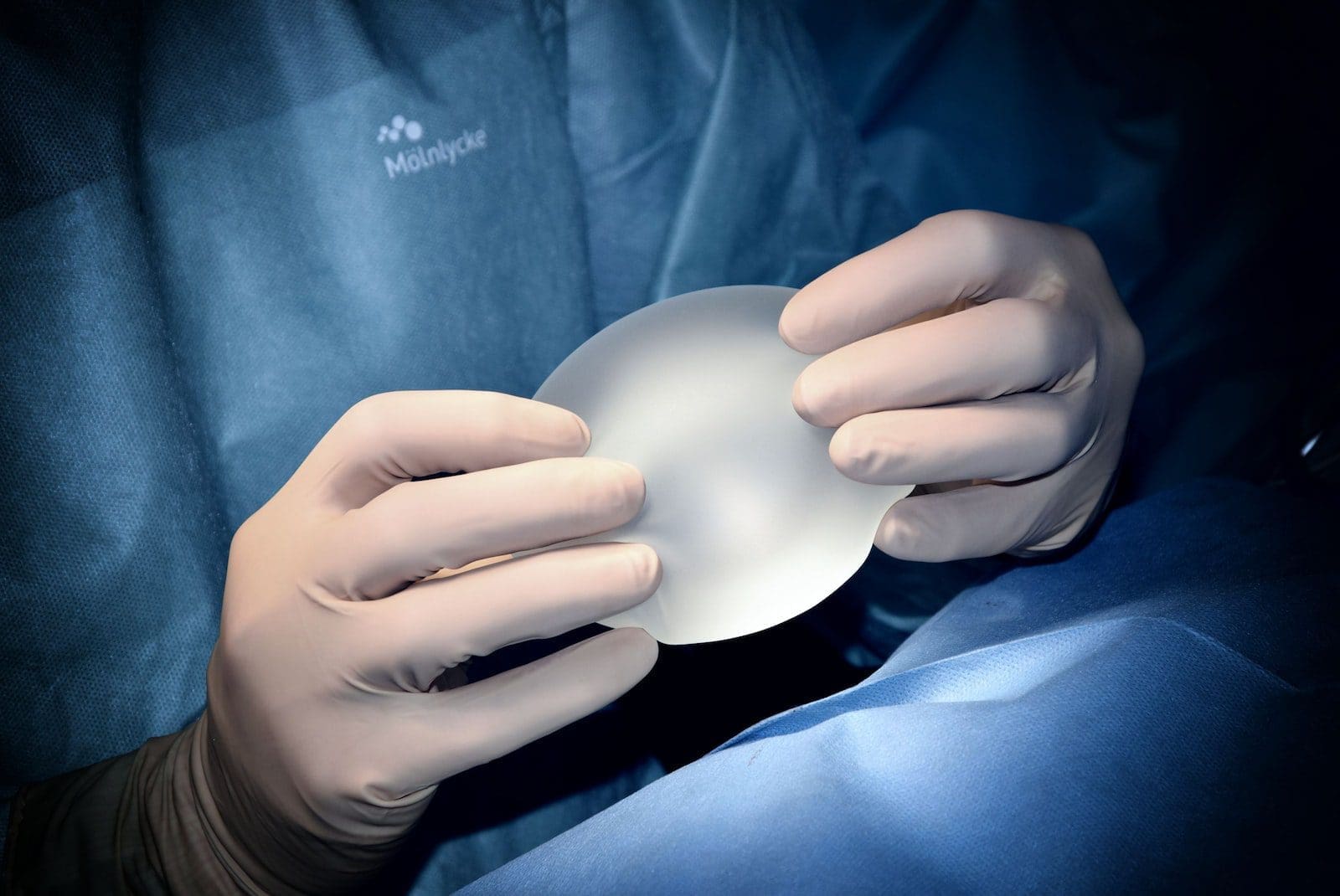 person holding white breast implant for cosmetic surgery
