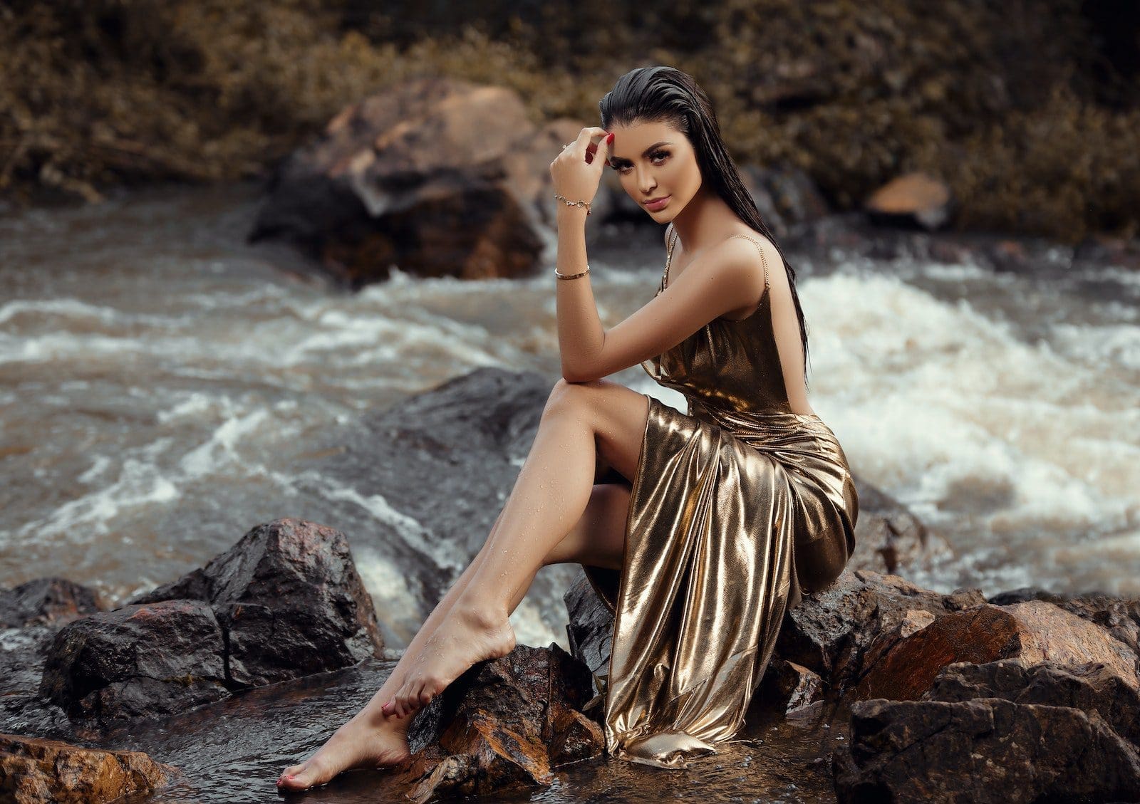 Photo of Woman in a Gold Gown party-wear Sitting on a Rock by the River