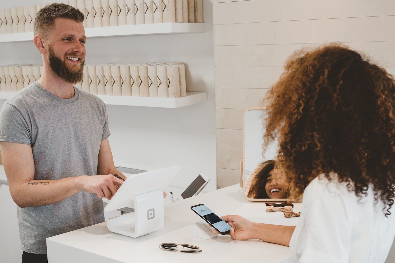 man in grey crew-neck t-shirt smiling to woman on counter customers and product management