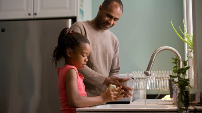 man in long sleeve shirt standing beside girl in pink tank top washing hands