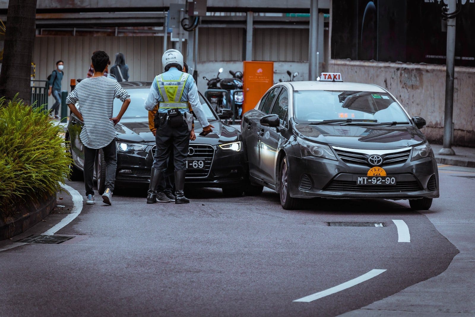 man in white and black stripe shirt and black pants standing beside black car during daytime accidents happen