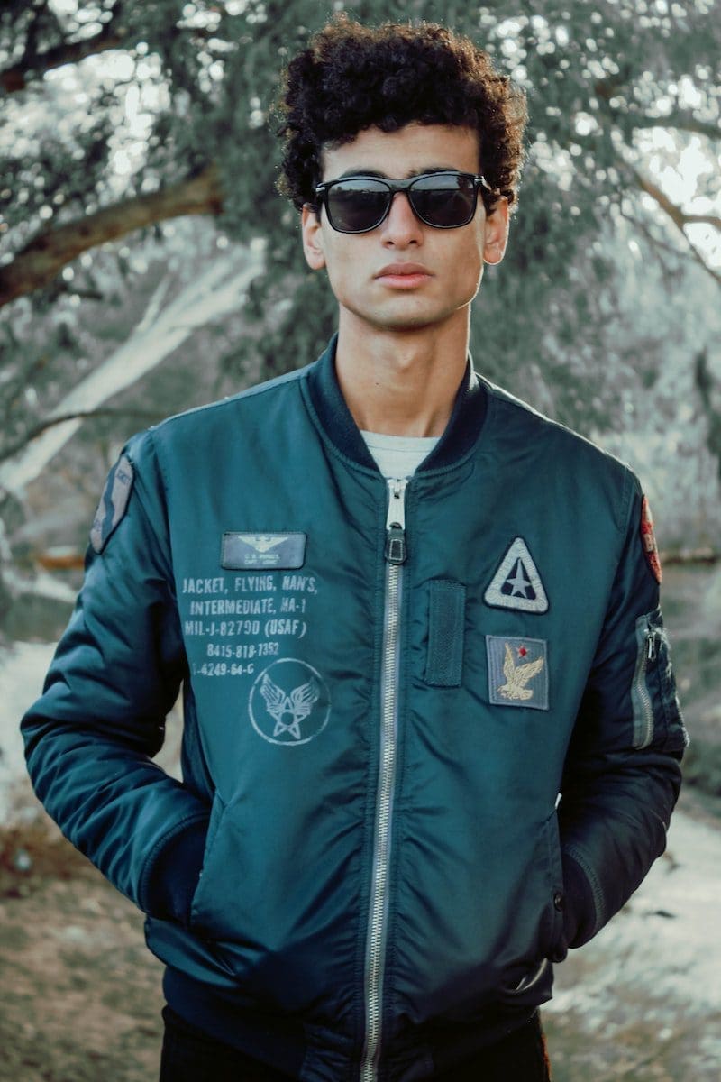 man wearing green bomber jackets while hands on pocket