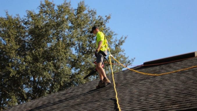 a man on a roof working with a rope roof measurements