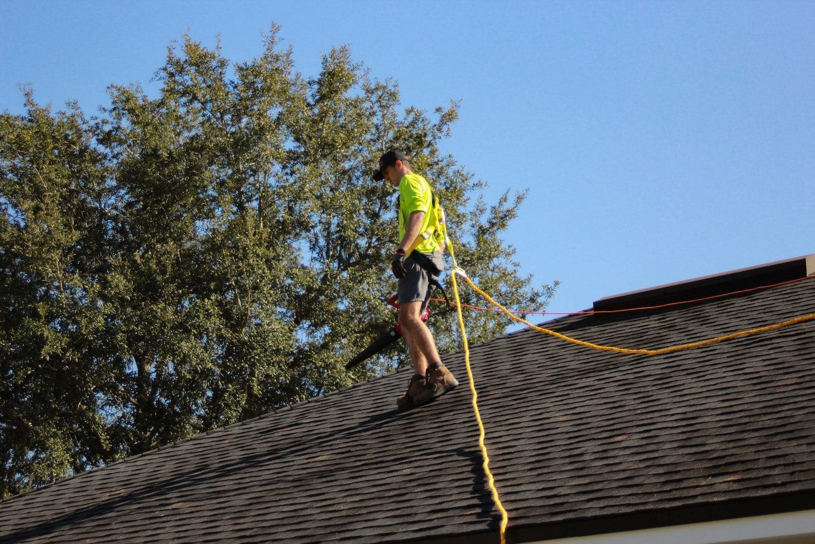 a man on a roof working with a rope roof measurements