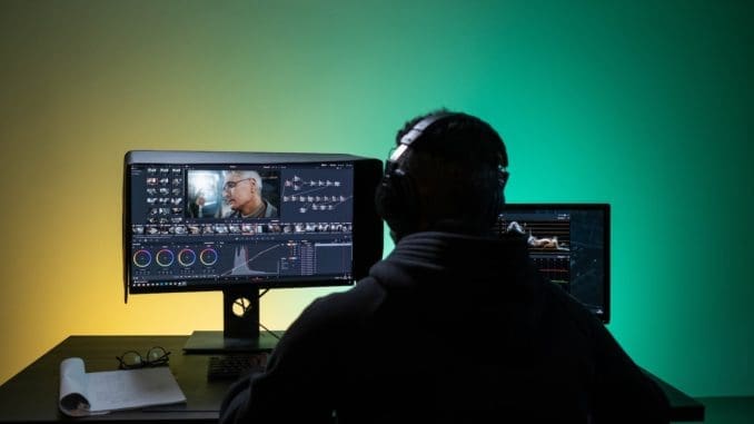 A Man Sitting on Front of the Computer while Editing Video