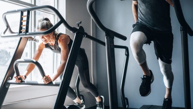 Photo by GRAHAM MANSFIELD woman in black tank top and black shorts sitting on black exercise equipment