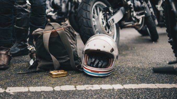 white helmet beside black backpack on road