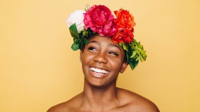 woman smiling wearing flower crown glowing skin