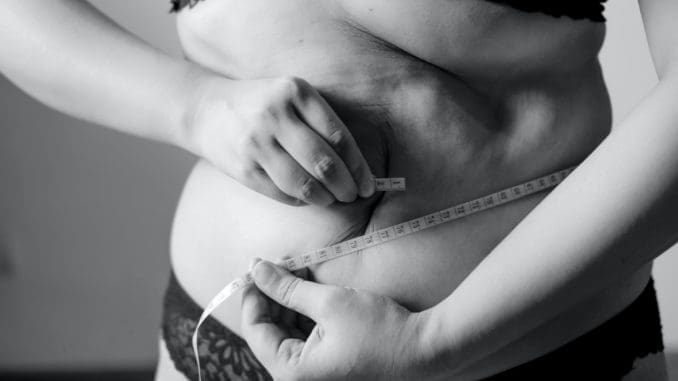 grayscale photo of woman holding her breast fat burning