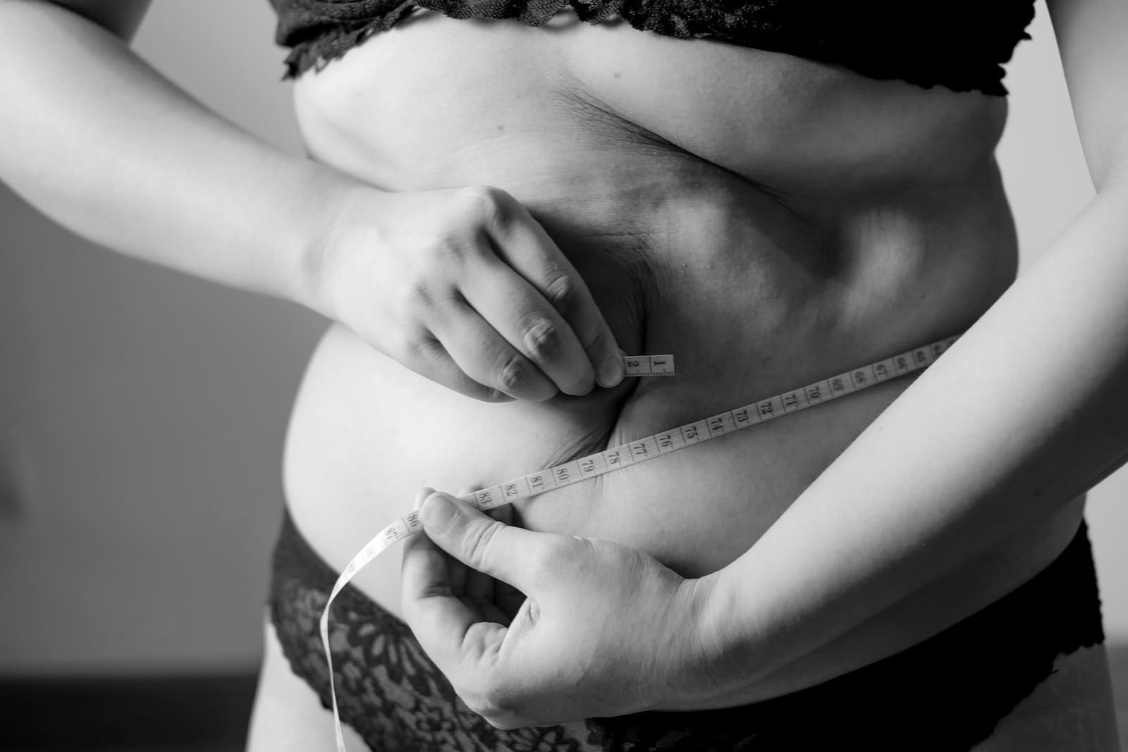 grayscale photo of woman holding her breast fat burning