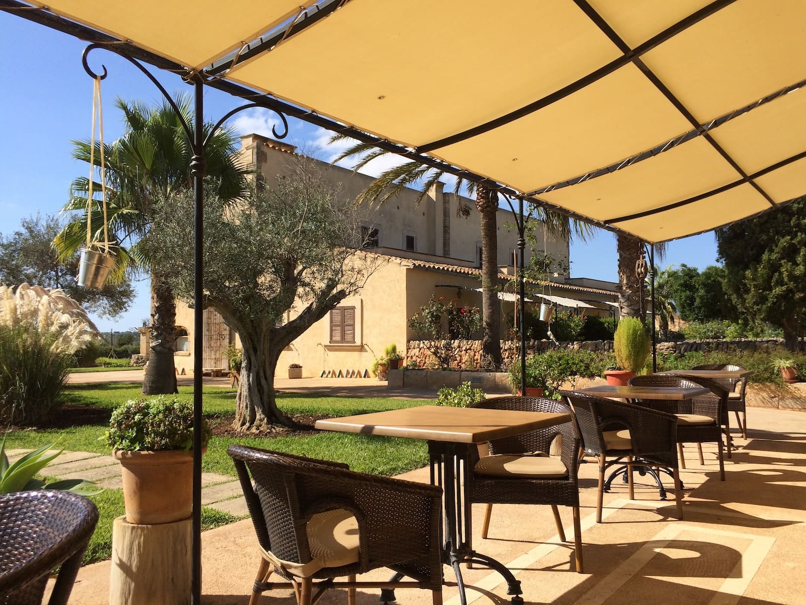 a patio with tables and chairs under an umbrella