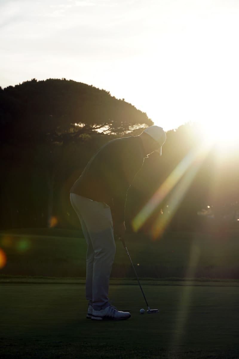 a person on a golf course with the sun in the background