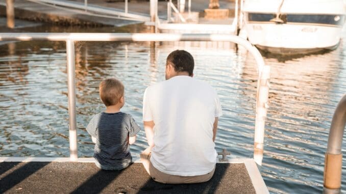 man and boy sitting on dock