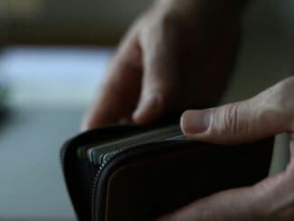 a person holding a wallet in their hand frugal
