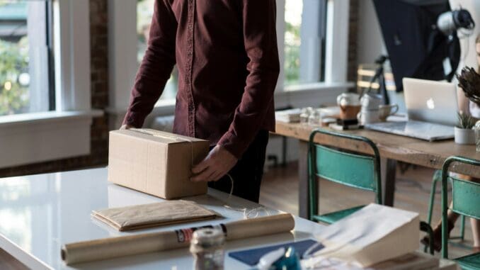 person holding cardboard box on table shipping and delivery