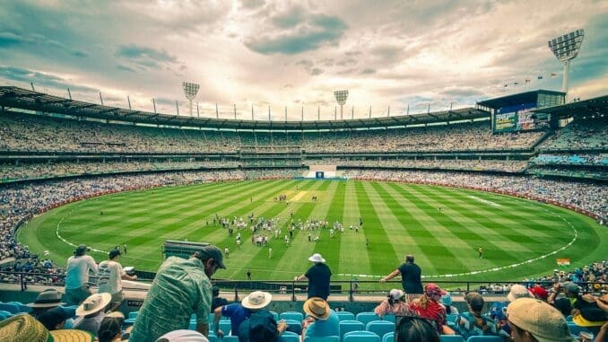 IPL 2024 A lively cricket match at Melbourne Cricket Ground with a colorful crowd under a dynamic sky.