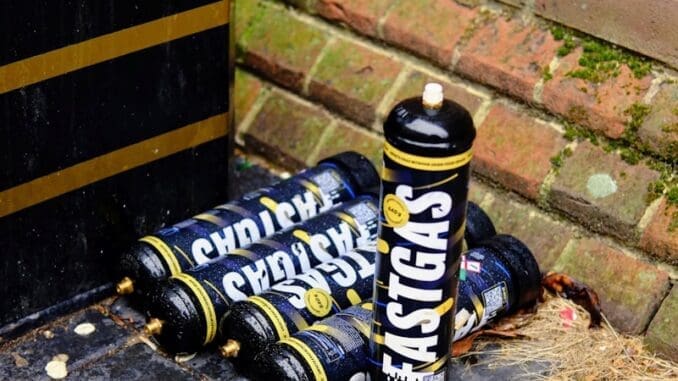 a couple of bottles sitting on the ground next to a brick wall